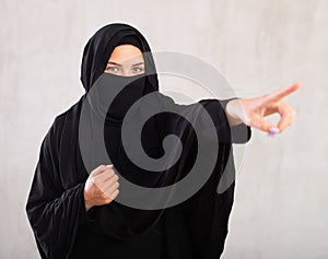 woman with her face covered by burka points her hand to side