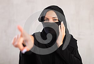 woman with her face covered by burka points her hand to side