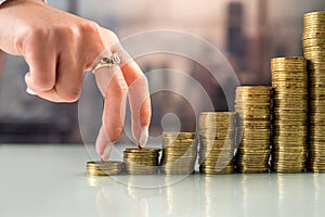 woman with her fingers going uphill on stacks of gold coins.