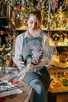 A woman in her florist shop collects bouquets of flowers. The concept of a small business. Bouquets of tulips for the