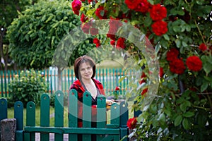 Woman in her garden among roses in the evening