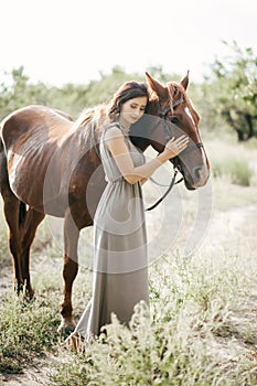 Woman with her horse on a lovely meadow lit by warm evening light. Animal love concept