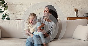 Woman her little daughter enjoy playtime sit on sofa indoor