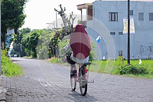 Woman on her old bicycle alone, going home after some morning ride in Yogyakarta