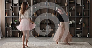 Woman her older mother wear fluffy skirts dancing at home