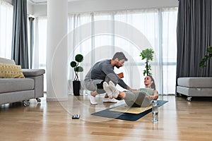 Woman with her personal fitness trainer. Couple exercising together. Man and woman in sports wear doing workout at home. Healthy
