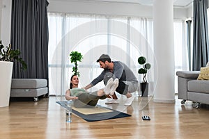 Woman with her personal fitness trainer. Couple exercising together. Man and woman in sports wear doing workout at home. Healthy