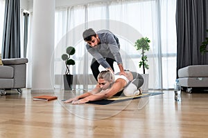 Woman with her personal fitness trainer. Couple exercising together. Man and woman in sports wear doing workout at home. Healthy