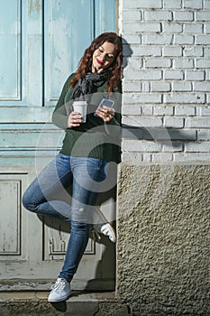 Woman with her smartphone and having coffee outside