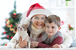 Woman and her son celebrating christmas with furry friend. Mother and kid with terrier dog. Pretty child boy with puppy at x-mas t