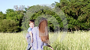 Woman with her son at the hands of goes on the field nature