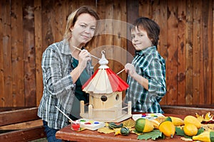 Woman and her son painting a bird house