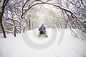 A woman with her son rides down the hill in a sleigh
