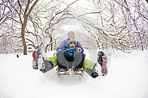 A woman with her son rides down the hill in a sleigh