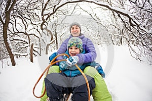 A woman with her son rides down the hill in a sleigh