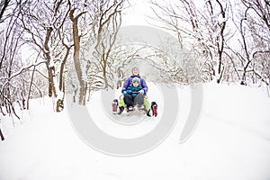 A woman with her son rides down the hill in a sleigh