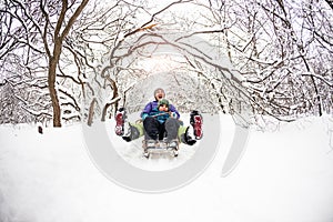 A woman with her son rides down the hill in a sleigh and screaming