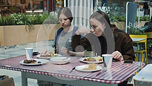 A woman and her teenage daughter have lunch at a shopping center restaurant.