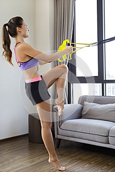 Woman during her workout at home with suspension straps