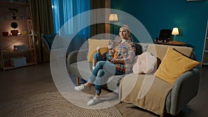 A woman and her young daughter are watching TV using a remote control. Mom and daughter sitting in an embrace in the