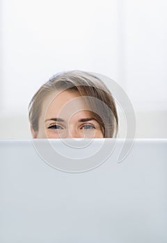 Woman hiding behind laptop