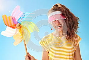 Woman hiding behind sun visor holding colorful windmill