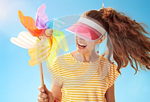 Woman hiding behind sun visor holding colorful windmill