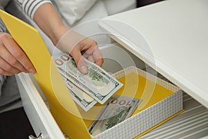 Woman hiding dollar banknotes in box at home, closeup