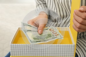 Woman hiding dollar banknotes in box at home. Money savings