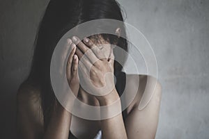 A woman hiding face. Violence against women concept. Depressed teenager sitting holding head in hands, stressed sad young woman