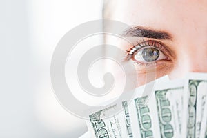 Woman hiding her face behind us dollar money fan
