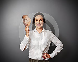 Woman hiding her good mood under sad mask