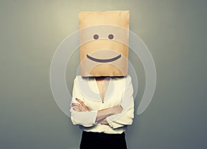 Woman hiding under smiley paper bag