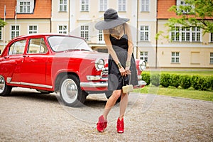 woman in high heals standing in front of retro car