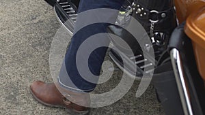 Woman in high heels sitting behind male biker on motorcycle, legs close up