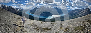 Woman on high mountain pass over the lake in Canadian Rockies.