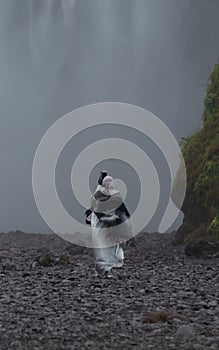 A woman in hijab - in front of SkÃ³gafoss waterfall