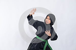 Woman in hijab in pencak silat uniform poses stance and fend off attacks with copyspace photo