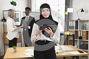 Woman in hijab posing at office during meeting