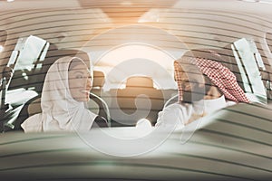 A woman in hijab sits near the Arab in a new car.