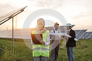 Woman in hijab writing on clipboard at solar station