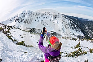 Woman hikeing in the snowy mountains with a phone and snowshoes. and backpack photo