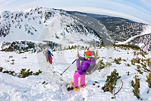 Woman hikeing in the snowy mountains with a phone and snowshoes. and backpack photo