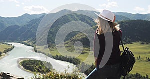 Woman hiker admiring picturesque nature view in mountains valley with river.