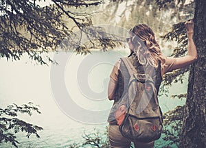 Woman hiker with backpack enjoying amazing mountain lake landscapes.