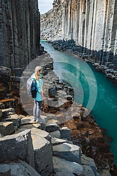 Woman hiker with backpack enjoying Studlagil Canyon. Unique Jokulsa basalt colums and A Bru river. Spectacular outdoor