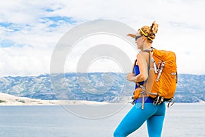 Woman hiker with backpack, hiking at seaside and mountains