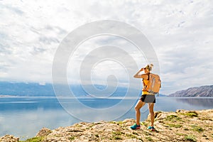 Woman hiker with backpack, hiking at seaside and mountains