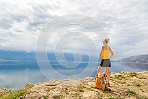 Woman hiker with backpack, hiking at seaside and mountains