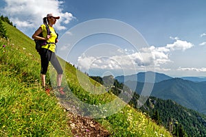 Woman hiker with backpack looking from hill
